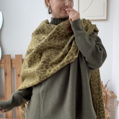 Lenço animal print castanho e verde claro com camisola verde oliva em mulher num ambiente interior