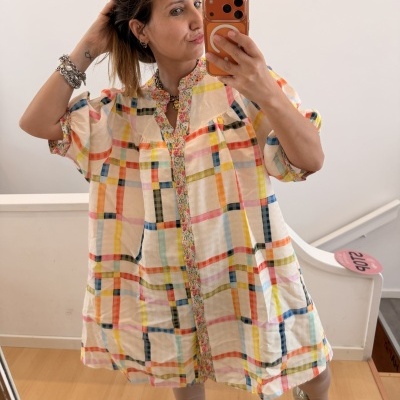 Vestido solto curto com riscas coloridas e gola floral em mulher a fazer selfie com telemóvel laranja