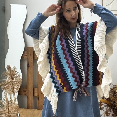 Mulher com capa de malha colorida e vestido azul