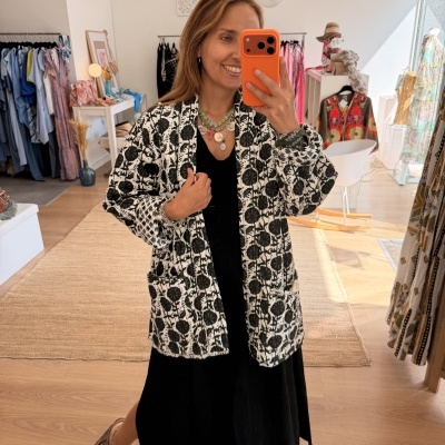 Mulher com casaco preto e branco tirando selfie numa loja de roupa