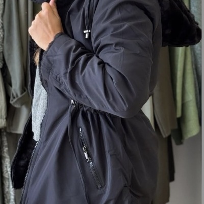 Casaco preto com capuz peludo e fechos, em modelo feminino
