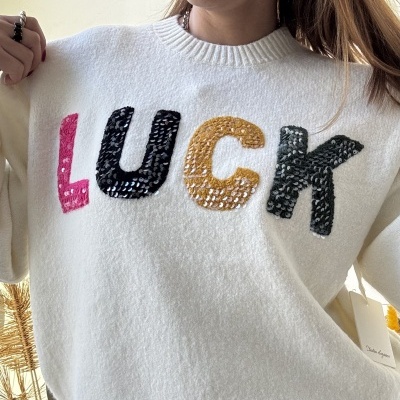 Camisola branca de malha com letras em lantejoulas formando a palavra LUCK