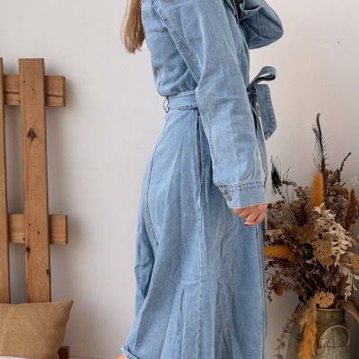 Vestido de ganga azul claro com cinto e ténis brancos com padrão em brilho dourado.