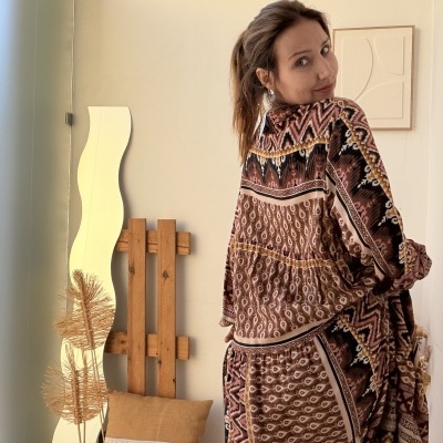 Vestido longo com padrão étnico castanho e preto em ambiente interior decorado