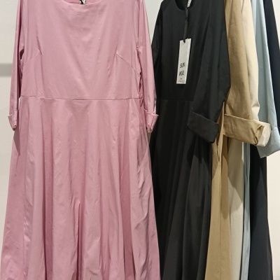 Vestidos lisos de vários tons pendurados em cabides numa loja