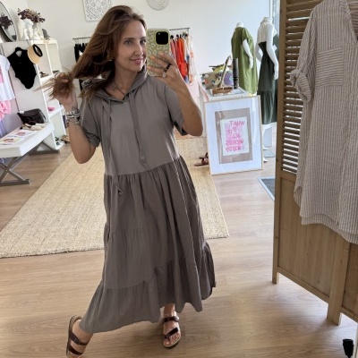 Vestido comprido taupe com capuz e sandálias castanhas em ambiente interior