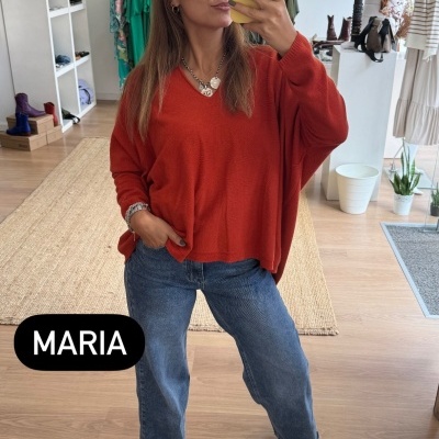 Mulher com camisola vermelha oversize e jeans azul a tirar selfie com telemóvel amarelo