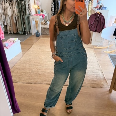 Macacão de ganga azul com alças castanhas usado por mulher a tirar selfie em loja de roupa