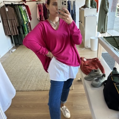 Mulher com camisola rosa e jeans a tirar selfie dentro de loja de roupa