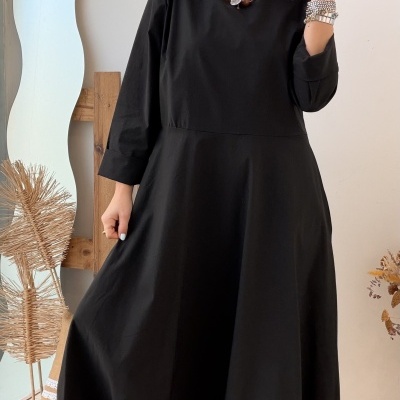 Mulher vestindo vestido preto comprido e botas castanhas