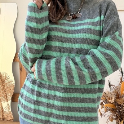 Mulher com pulôver listrado verde menta e cinza em ambiente interior
