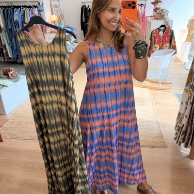 Vestidos coloridos tie-dye em loja com chão de madeira