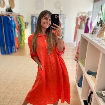 Mulher veste vestido midi laranja de linho com bolsos, na loja de roupas moderna