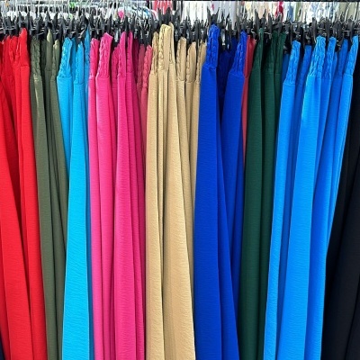 Calças de várias cores penduradas em cabides numa loja