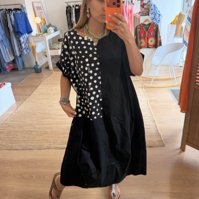 Vestido preto com bolinhas brancas no espelho em loja de roupas.