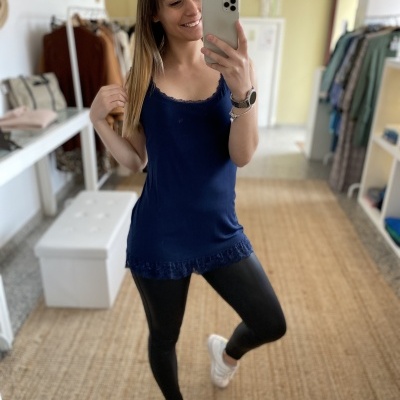 Mulher com camisola azul e leggings pretas a tirar selfie em espelho