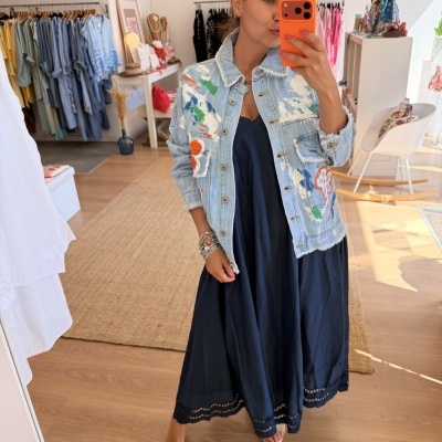Casaco jeans azul claro com pintura colorida e vestido azul escuro em loja