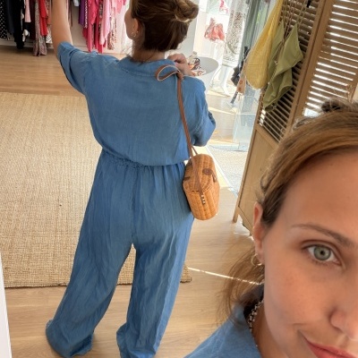 Pessoa de macacão azul claro a tirar selfie em espelho numa loja de roupa