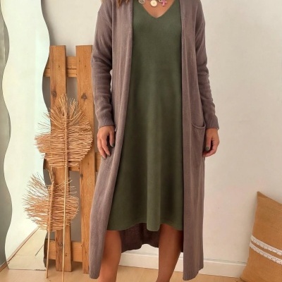 Mulher vestindo vestido verde caqui, casaco longo castanho de malha e ténis bege com glitter dourado