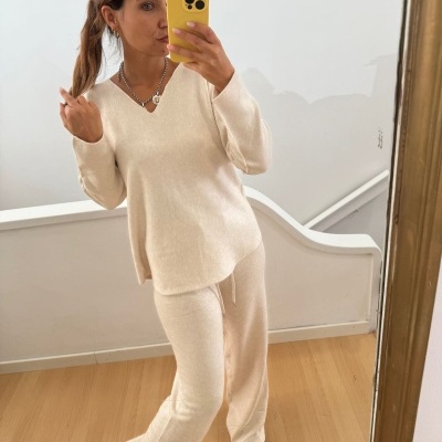 Mulher com conjunto creme de malha fina com camisola de manga comprida e calças largas a tirar selfie em espelho