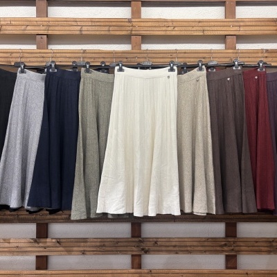 Saias plissadas em tons neutros e escuros penduradas em varão de madeira.