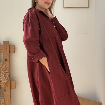 Vestido vermelho vinho de manga comprida com bolso, usado por mulher em ambiente interior