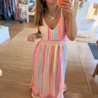 Vestido comprido colorido com padrão geométrico usado por mulher numa loja de roupa