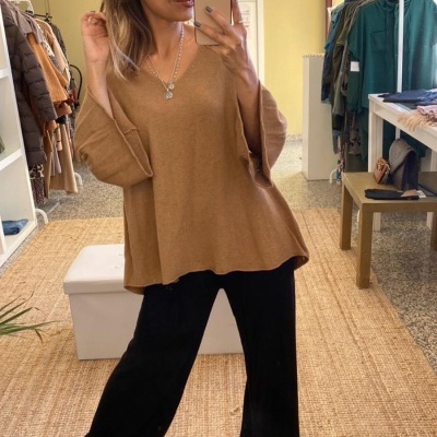 Mulher com camisola castanha e calças pretas numa loja de roupas