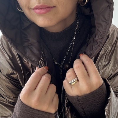 Mulher com casaco acolchoado castanho metálico e acessórios dourados e prateados