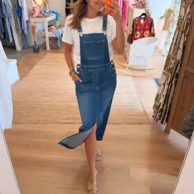 Vestido salopete de ganga azul médio com bolso frontal e botão em loja de roupa