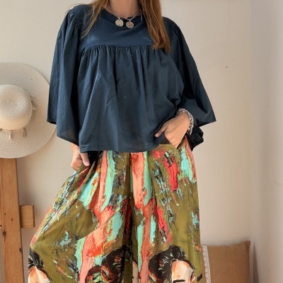 Mulher com blusa azul escura e calças largas com padrão colorido