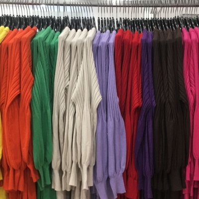Camisolas de malha coloridas penduradas em cabides numa loja.