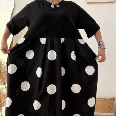 Vestido preto com bolinhas brancas usado por mulher num interior.