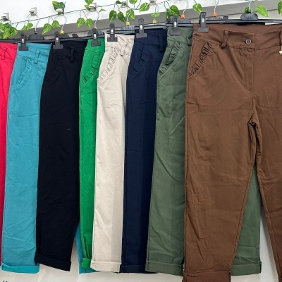 Calças coloridas penduradas em cabide com plantas verdes ao fundo