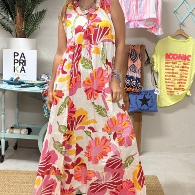 Mulher de vestido maxi floral em ambiente com roupas e plantas