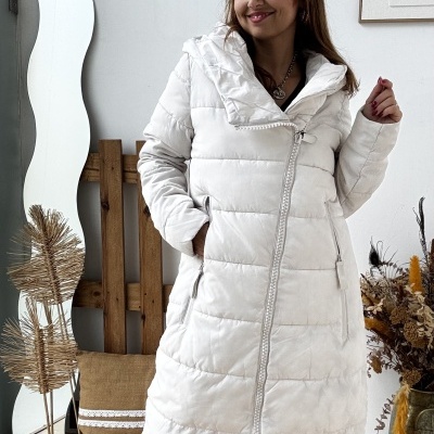 Mulher com casaco acolchoado branco comprido e botas castanhas em ambiente interior