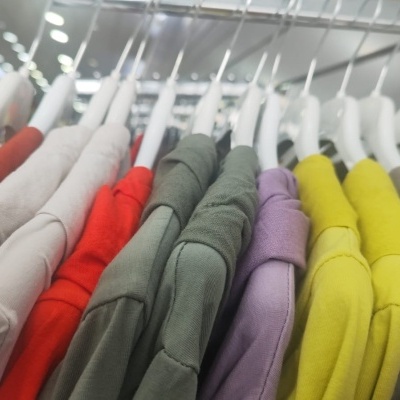 Camisas de manga longa coloridas penduradas em cabides brancos num cabide metálico