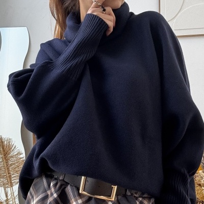 Mulher com camisola preta e calças xadrez castanho-bege, decoração interior neutra