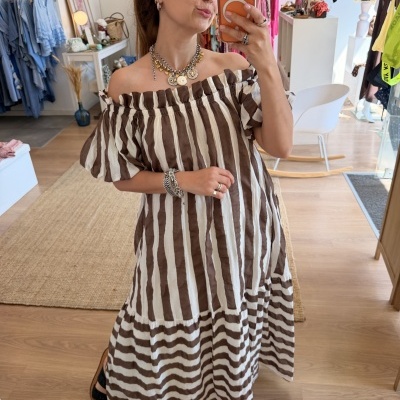 Vestido ombro a ombro castanho e branco às riscas usado por mulher a tirar selfie em loja de roupa