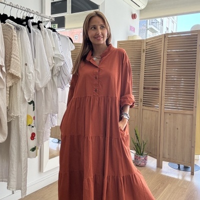 Vestido comprido terracota com botões e pregas usado em ambiente interior