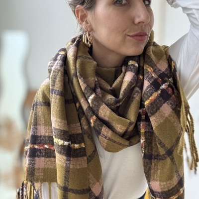 Lenço xadrez em tons de verde, castanho e rosa com franjas, usado por mulher com blusa branca