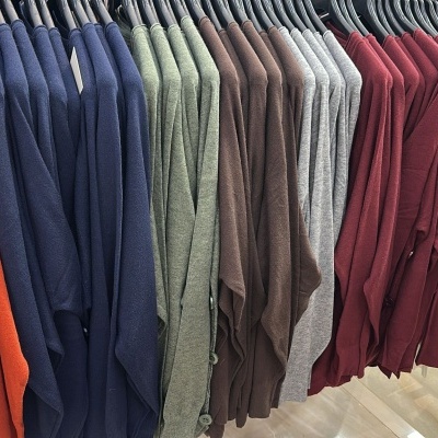 Casacos ou camisolas de malha coloridas penduradas em cabides numa loja