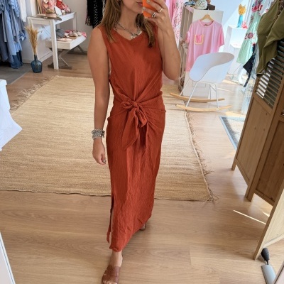 Vestido vermelho terracota com nó usado por mulher a tirar selfie numa loja de roupa