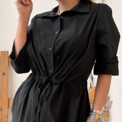 Vestido preto com botões e cordão na cintura usado por mulher com pulseiras.