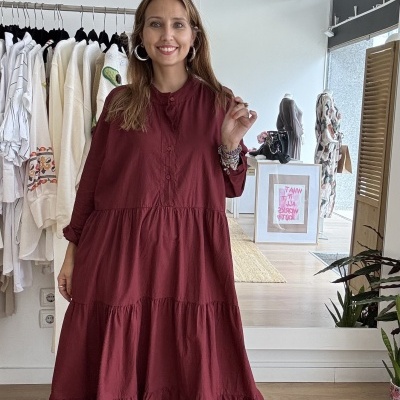 Mulher a usar vestido longo vinho com ténis brancos em loja de roupa