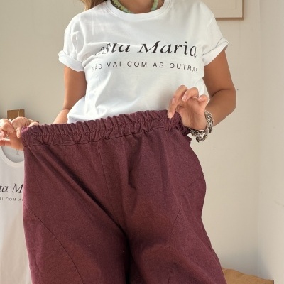 Mulher com t-shirt branca estampada e calças largas bordeaux