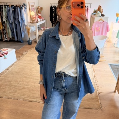 Mulher com roupa de ganga a tirar selfie numa loja de roupa