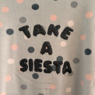 Manta cinza com bolinhas coloridas e texto preto acolchoado