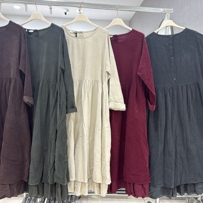 Cinco vestidos de tecido leve com mangas compridas dobradas em várias cores expostos em cabides