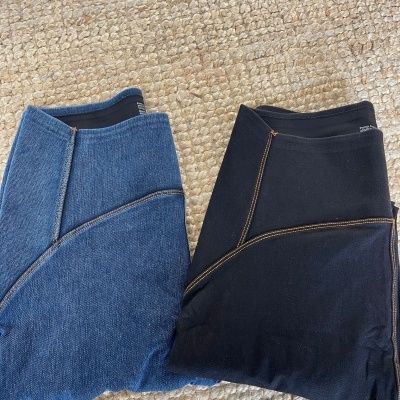 Dois pares de leggings azul e preto com costuras castanhas, sobre tapete bege texturizado